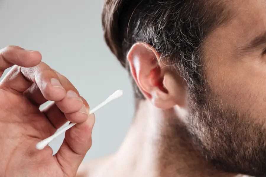 A man using a cotton bud to remove ear wax